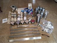 Overall view of all items laid out on floor, including magnetic bars, canisters, drawer pulls, decorative ashtray, bath mat, tissue box, drawer liner, nightlight, and other small bathroom items.