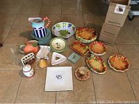 Image showing full collection of dishware including plates, bowls, jugs, dishes, and cups arranged on floor with white plate labeled '45'