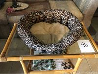Leopard print round cat bed on glass table with lightly padded beige cushion inside showing size and condition.