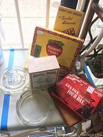 Set of four vintage cigar boxes and two glass ashtrays on white surface with blue stripe.