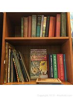 Shelf with assorted vintage and antique books, including novels and children's books, alongside vintage comic books and a shorthand dictionary.