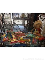 Wide view of assorted Pez dispensers scattered on black metal surface with Holly Hobby doll on the right side, showing arrangement and condition.