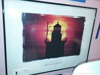 Framed signed print showing lighthouse silhouette at sunset, signed by Kevin Fleming