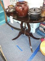 Dark wooden harp table with various decorative ceramic and cast iron pots on top.
