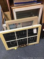 Photo of assorted old windows stacked together, one painted yellow and converted into chalkboard with writing "Reclaimed Historic Window Chalkboard from Lewes."