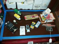 All four vintage tin toy cars in different colors plus other items on a dark table