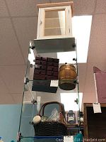 Overview photo showing curio cabinet on top of glass display case, jewelry box, wooden barrel inside the case, and basket with assorted doorknobs below.