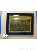 Framed artwork depicting a battle scene with soldiers, including blue matting and black frame.