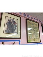 Two framed prints hanging on a wall with a seashell border above. Left print is Norman Rockwell print, right print is State of Delaware original with green 'original' sticker.