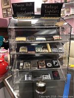 Front view of clear acrylic vintage lighter display case containing multiple lighters with key attached to case lock