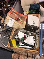 Photo of stained glass foiler box, electric foiler unit, foiling tool and assorted stained glass pieces inside a wooden box.