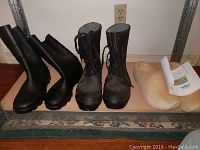 Front view of three pairs of men's shoes: rubber rain boots, Hutchson work boots, and wooden clogs.