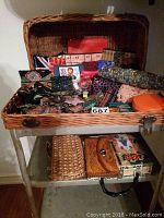Wide shot of wicker basket on a metal table filled with various coin purses, keychains, and a handbag below