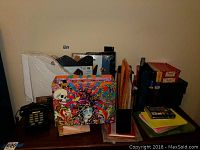 Photo showing the entire lot including Ed Hardy box, file organizers, spiral notebooks, and other stationery items arranged on a surface against wall.