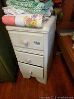 Nightstand closed showing off white painted surface and three drawers with knob handles.