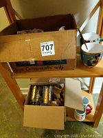 Box containing Christmas mugs and glasses on wooden shelf