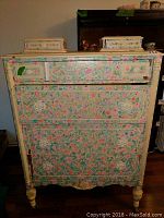 Front view of the chest showing the floral painted design across the entire surface and all drawers closed.