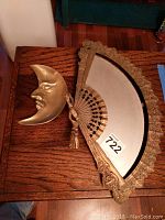 Top down photo of brass crescent moon dish and crescent moon wall mirror on wooden table
