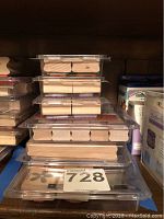 Multiple stacks of small wooden-handled square rubber stamps in clear plastic cases, showing assorted designs from the top.