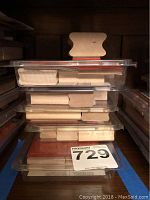 Stack of five clear plastic containers filled with assorted rubber stamps