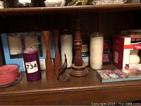 Wide view showing wooden decorative items, candles, wax cubes, LED candles boxed set, and scented candles on wooden shelf.