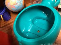 Close-up of the interior of the turquoise turtle-shaped toy chest, showing molded compartment shapes.