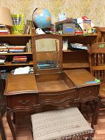 Front view of antique wooden dressing table with central mirror, showing two drawers open and upholstered seat in front.