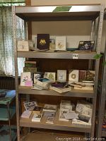 Wide view of metal shelving unit filled with multiple stationary items including writing papers, envelopes and various greeting cards.