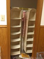 Photo of 2 beige cloth hanging storage organizers with multiple shelves hung from a green rod top, placed in front of a mirror.