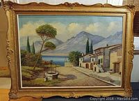 Full view of the large antique oil painting showing the entire lake and mountain landscape inside the ornate gold frame.