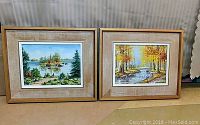 Pair of original oil paintings in oak frames depicting different scenic landscapes placed side by side.