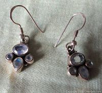 Front view of two vintage sterling silver dangling earrings with four rainbow moonstones each, showing shape and setting.