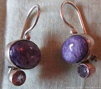 Close-up of the front view showing the round charoite cabochon on top and smaller light amethyst below each earring in sterling silver settings with hook backs.