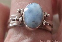 Close-up view of oval larimar cabochon set in sterling silver ring on finger