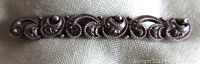 Top view of the silver scroll style pin displaying marcasite stones and intricate design.