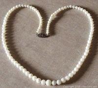 Full view of the round cream-colored pearl necklace laid out showing varying bead sizes and clasp.