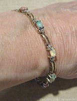 Sterling silver synthetic opal cabochon link bracelet worn on wrist showing the opal colors and link design.