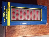Image of the hone knife blade sharpener through the transparent window of the box showing the four-sided sharpening surface with red oval grooves.