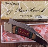 Folded view of Jim Frost Razor Hawk II knife in original box showing wooden handle with red Jim Frost signature inlay and packaging.