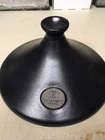 Close-up of the conical black glazed ceramic lid showing the Emile Henry France logo embossed in the center.