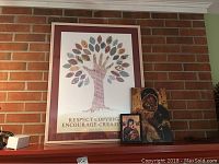 Wide shot showing all three framed pieces on a mantle: largest print with hand-tree design, two smaller Russian icon replicas in front.