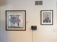 Both framed bicycle-themed prints hanging on wall, one larger 22x22 and one smaller 9x13, with visible telephone mounted below artworks.