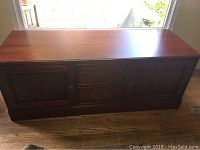 Full front view of the wooden entertainment center showing two center drawers and two cabinet doors on either side.