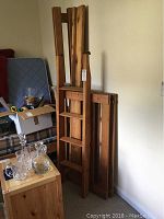 Folded wooden bunk bed frames stacked upright against wall