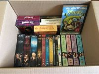 Top-down view of the full collection in a box showing Buffy the Vampire Slayer DVDs, Gilmore Girls, Charmed, Smallville, The Mentalist, Hairspray and Shrek DVDs.