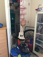 View showing closet door with hanging wire organizers, fabric cubby organizer, handbags, laundry basket, and folded sun shade screens.