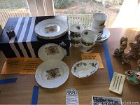 Overview of the set showing stacks of dessert plates, teacups and saucers arranged on a table with note cards.