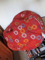 Top view of one bean bag chair with red fabric and colorful floral/firework print.