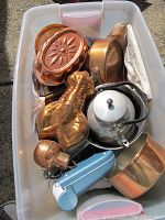 Top view photo showing assortment of copper plated molds, pots, metal kettle with black handle, and a blue and white Igia hair removal device.