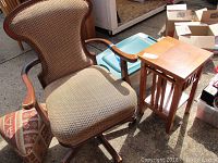 Wood framed upholstered rolling office chair next to wood side table and bamboo hamper